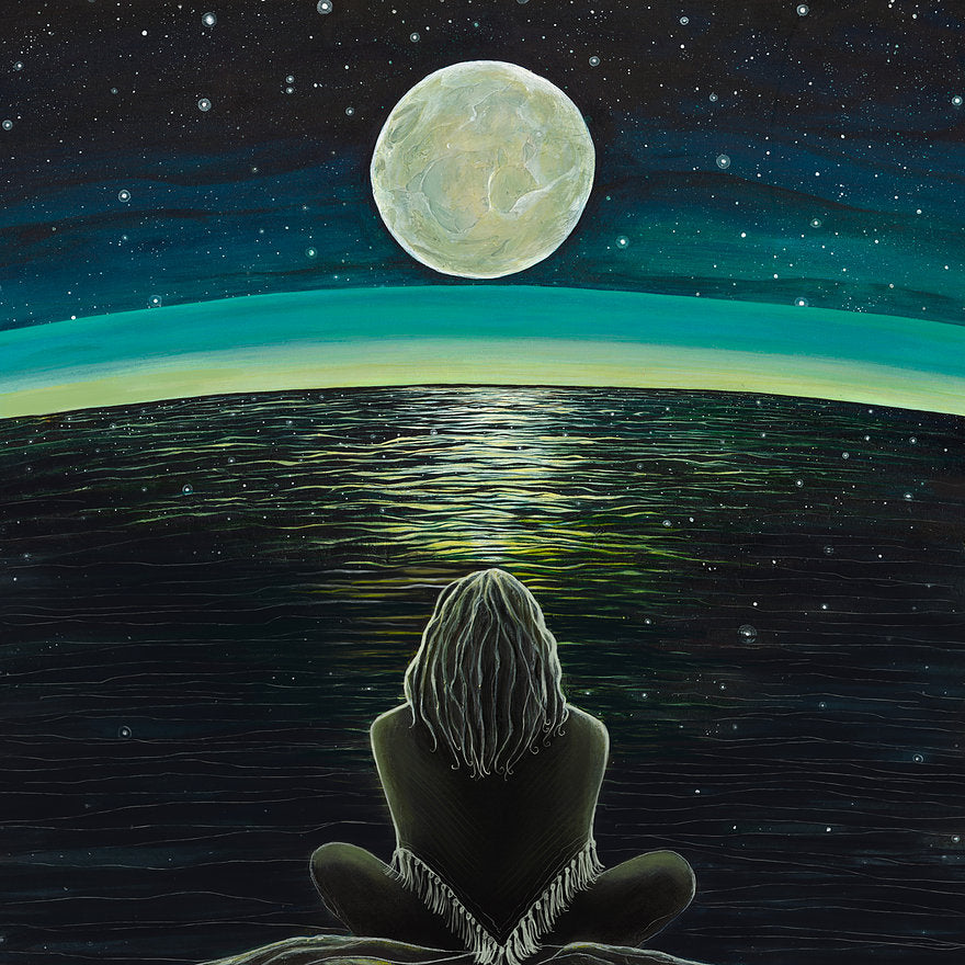 Person sitting on a rock gazing at a large moon over a starry night sky.